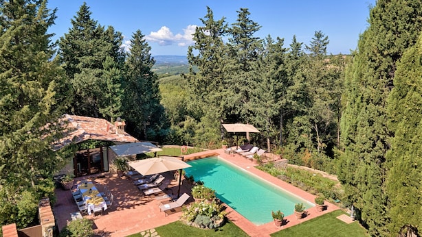 Un espace piscine offrant une vue dégagée sur le paysage environnant, notamment sur les arbres et les montagnes au loin.
