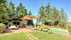 Un jardin avec une piscine, un espace salon extérieur et un chemin en pierre.