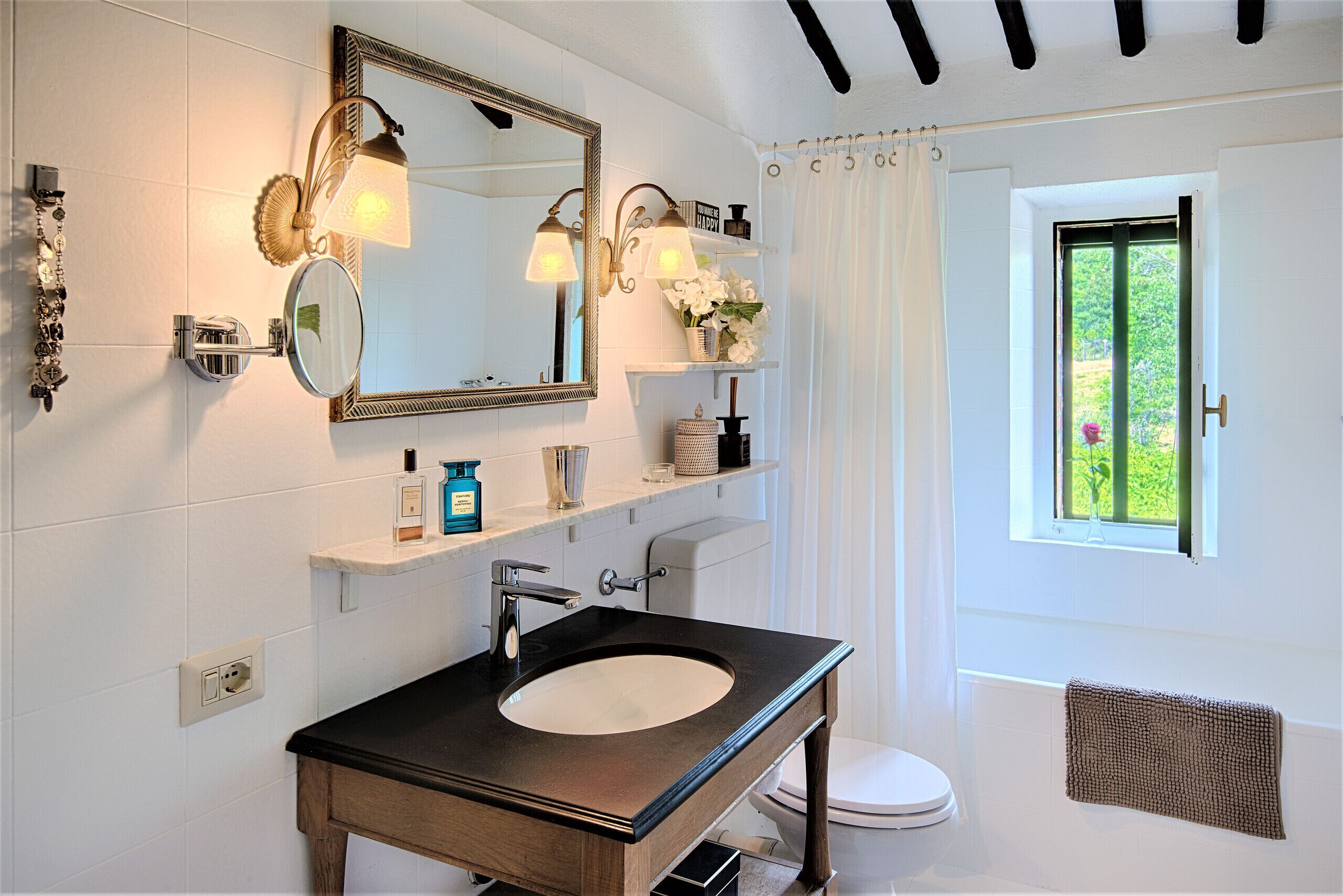 A bathroom with a large mirror, a sink, and a window.