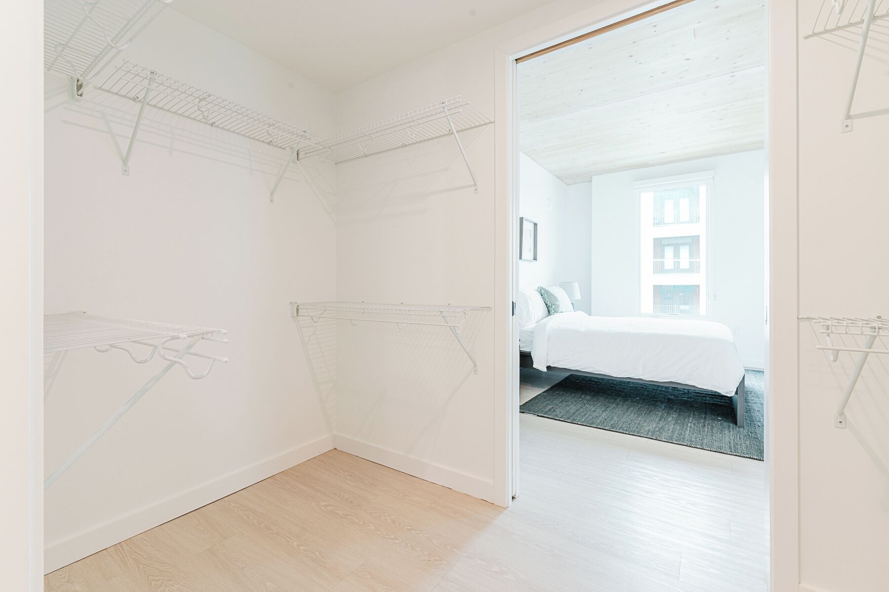 Una habitación con una cama, una puerta que da a otra estancia y un techo con estructura de cuadrícula.