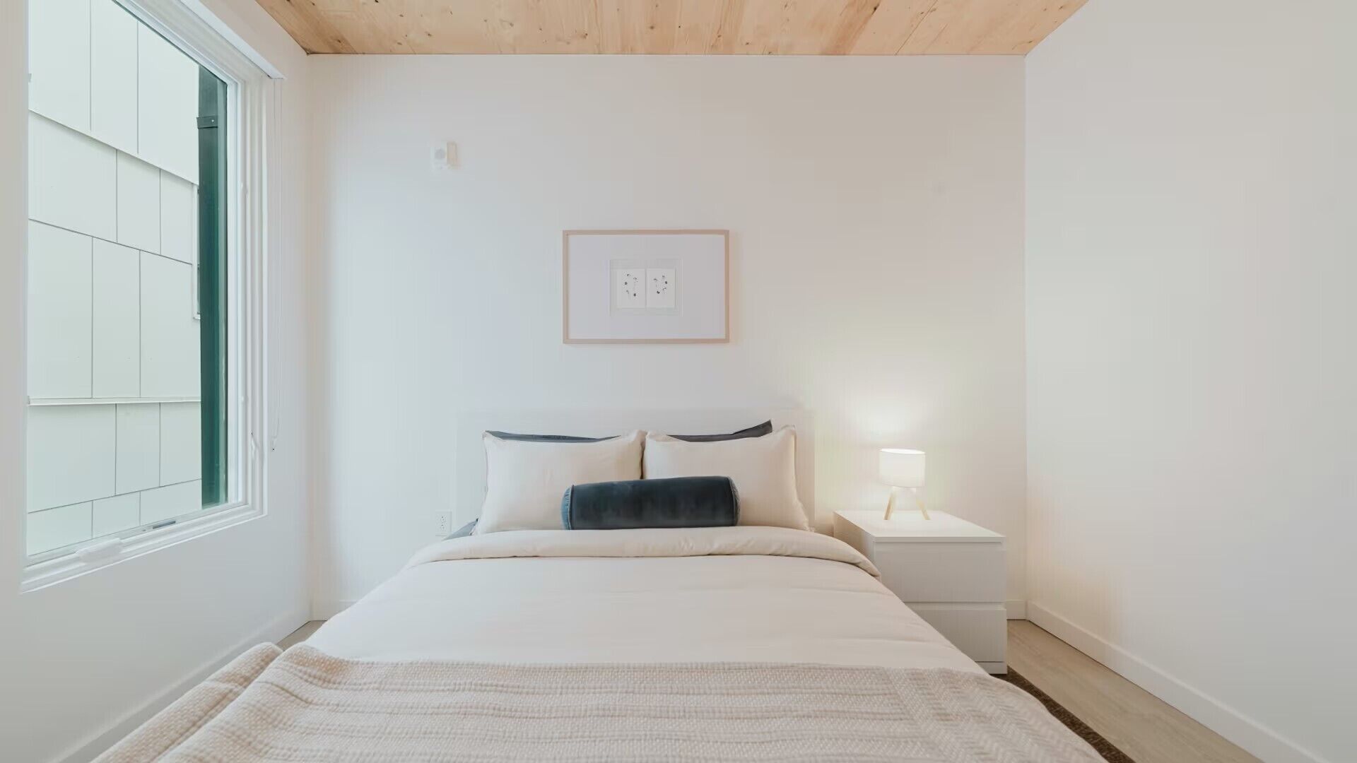 Un dormitorio con cama, mesita de noche y ventana.