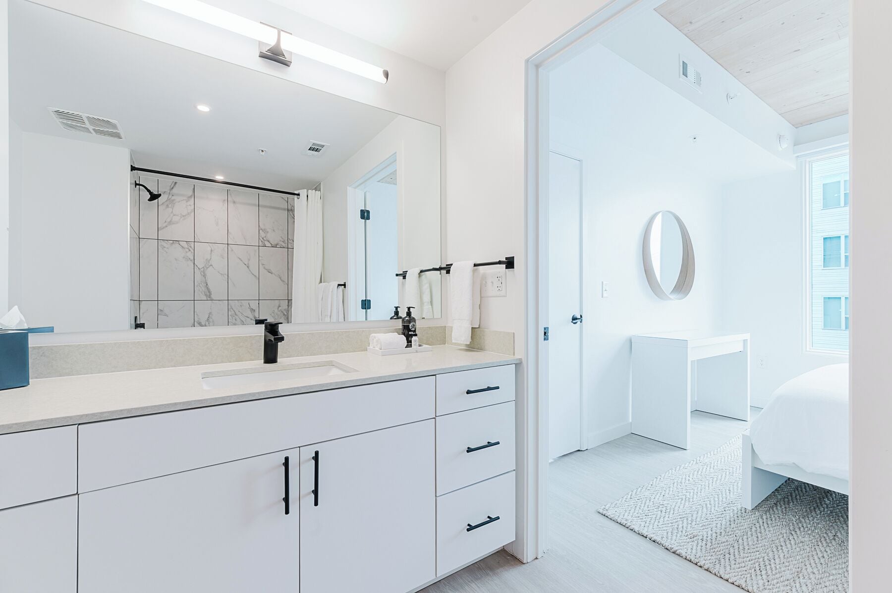 Un baño moderno con un espejo grande, una bañera y un inodoro.