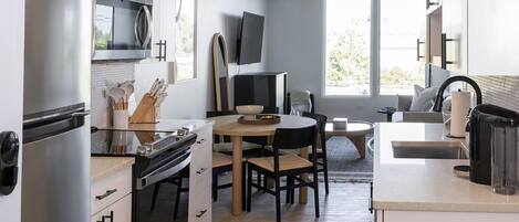 A modern kitchen with a refrigerator, stove, microwave, and a dining area with a table and chairs.