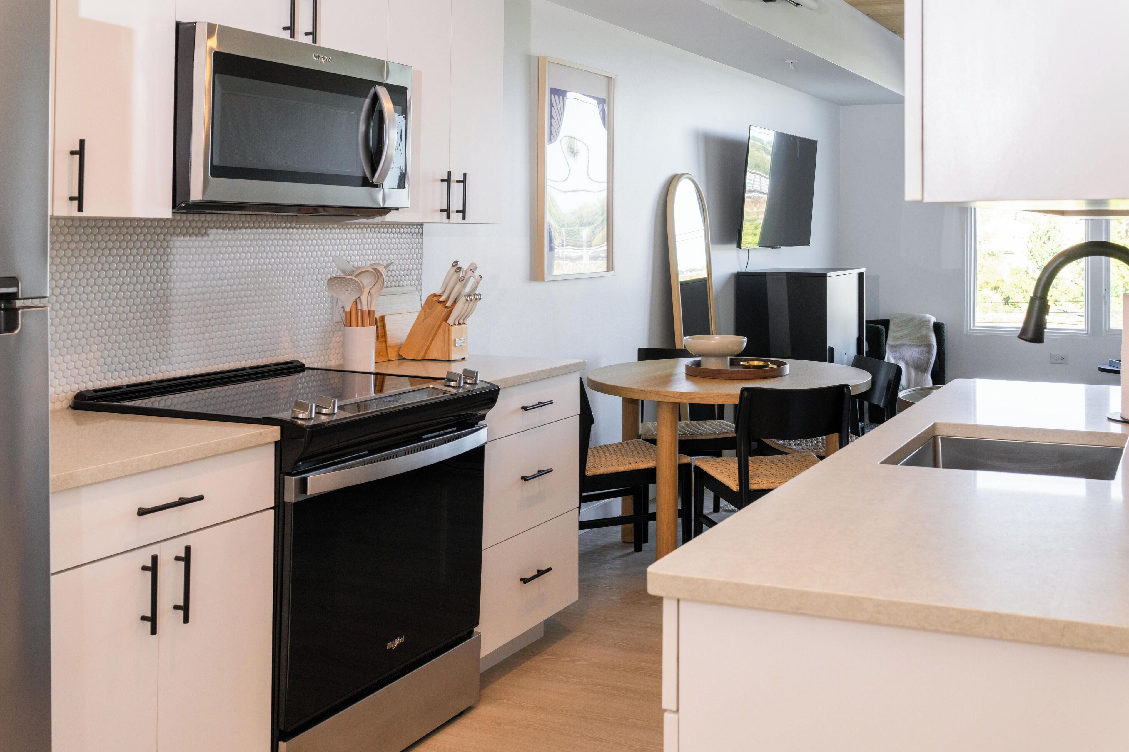 Una cucina moderna con elettrodomestici in acciaio inossidabile, un'area pranzo con tavolo rotondo e un'ampia finestra che offre luce naturale.