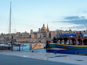 Ein Hafen mit einem großen Kreuzfahrtschiff, im Hintergrund ein markantes Kuppelgebäude und ein klarer Himmel.