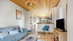 Een woonkamer met een bank, een salontafel, een televisie en een keuken op de achtergrond.