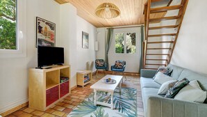 Een woonkamer met een flatscreen televisie, houten kasten, een salontafel, een bank en een trap.