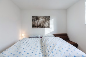 A bedroom with a bed, a chair, a nightstand, and a wall-mounted picture. - Apartment "Südstadt" with Wi-Fi (Villingen-Schwenningen)