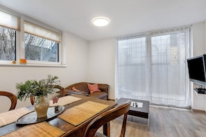 A dining area with a table, chairs, a vase with greenery, and a television in the corner. - Apartment "Südstadt" with Wi-Fi (Villingen-Schwenningen)