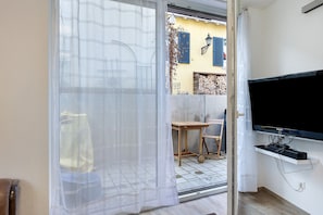 A room with a sliding glass door, a television mounted on the wall, and a small table with a chair. - Apartment "Südstadt" with Wi-Fi (Villingen-Schwenningen)