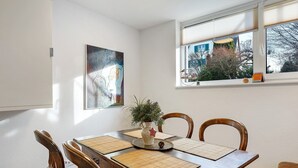 Ein Essbereich mit einem Holztisch, Stühlen, einer Pflanze in einer Vase und einem Bild an der Wand.
