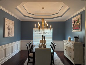 A dining room with a chandelier, a table, chairs, a cabinet, and artwork on the walls. - 3 Beds, 2.5 Baths+Fenced Yard for Family & Pets (Port Wentworth)