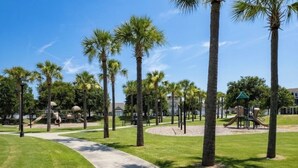 Un parc avec des palmiers, une aire de jeux et un sentier pédestre.