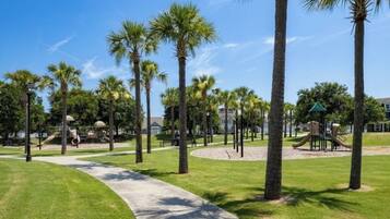 Un parque con palmeras, un parque infantil y un sendero para caminar.