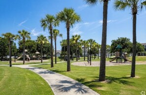 A park with palm trees, a playground, and a walking path.