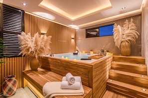 Un moderno cuarto de spa con sauna de madera, bañera de hidromasaje y televisor montado en la pared.