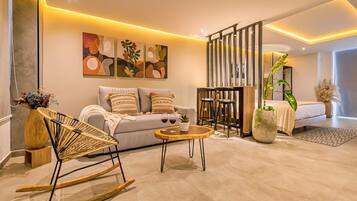 Una sala de estar moderna con un sofá, un sillón mecedora, una mesa de centro y una pared decorativa con arte abstracto.