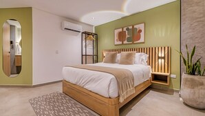 A modern bedroom with a bed, bedside tables, a mirror, and a large potted plant. - Amaris del Lili (Cali)
