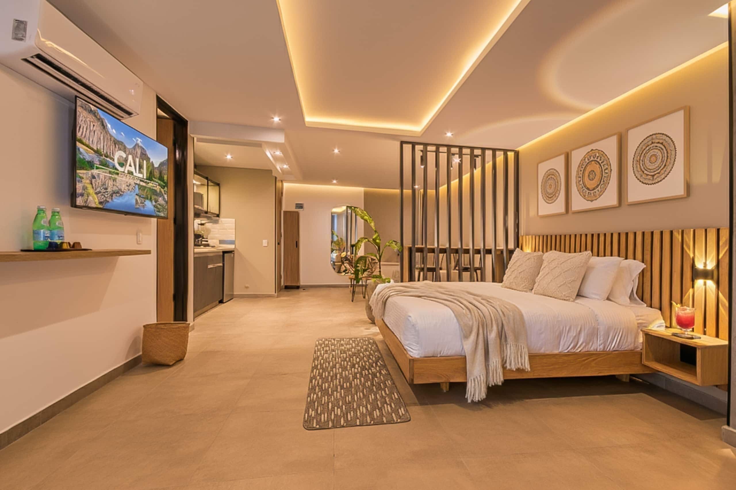 A modern hotel room with a bed, bedside table, TV, and artwork.