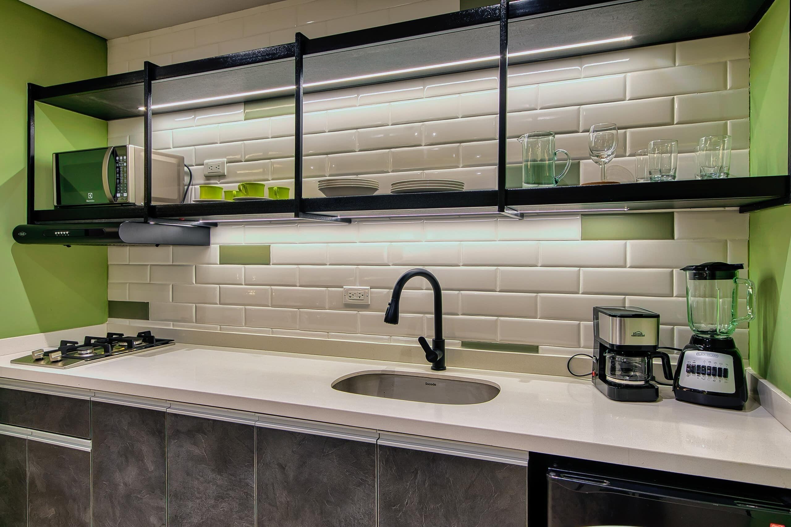 A modern kitchen with a built-in microwave, a coffee maker, and a blender on the countertop.