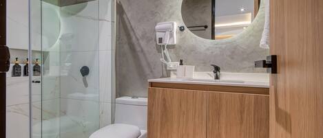 A modern bathroom with a glass-enclosed shower, a toilet, a vanity with a mirror, and a towel hanging on the wall.