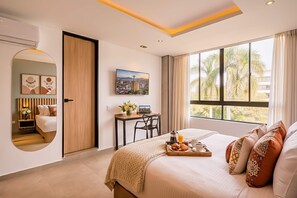 A modern bedroom with a large bed, a desk, a view of palm trees, and a cityscape painting. - Amaris del Lili (Cali)
