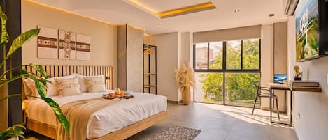 Ein modernes Schlafzimmer mit einem großen Bett, einem Essbereich und Blick auf Grünflächen.