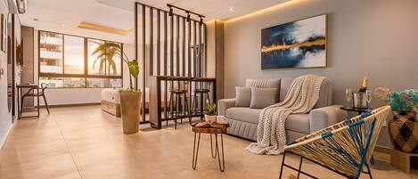 Un salon moderne comprenant un canapé, une table basse, un fauteuil à bascule et une grande fenêtre donnant sur un beau paysage.