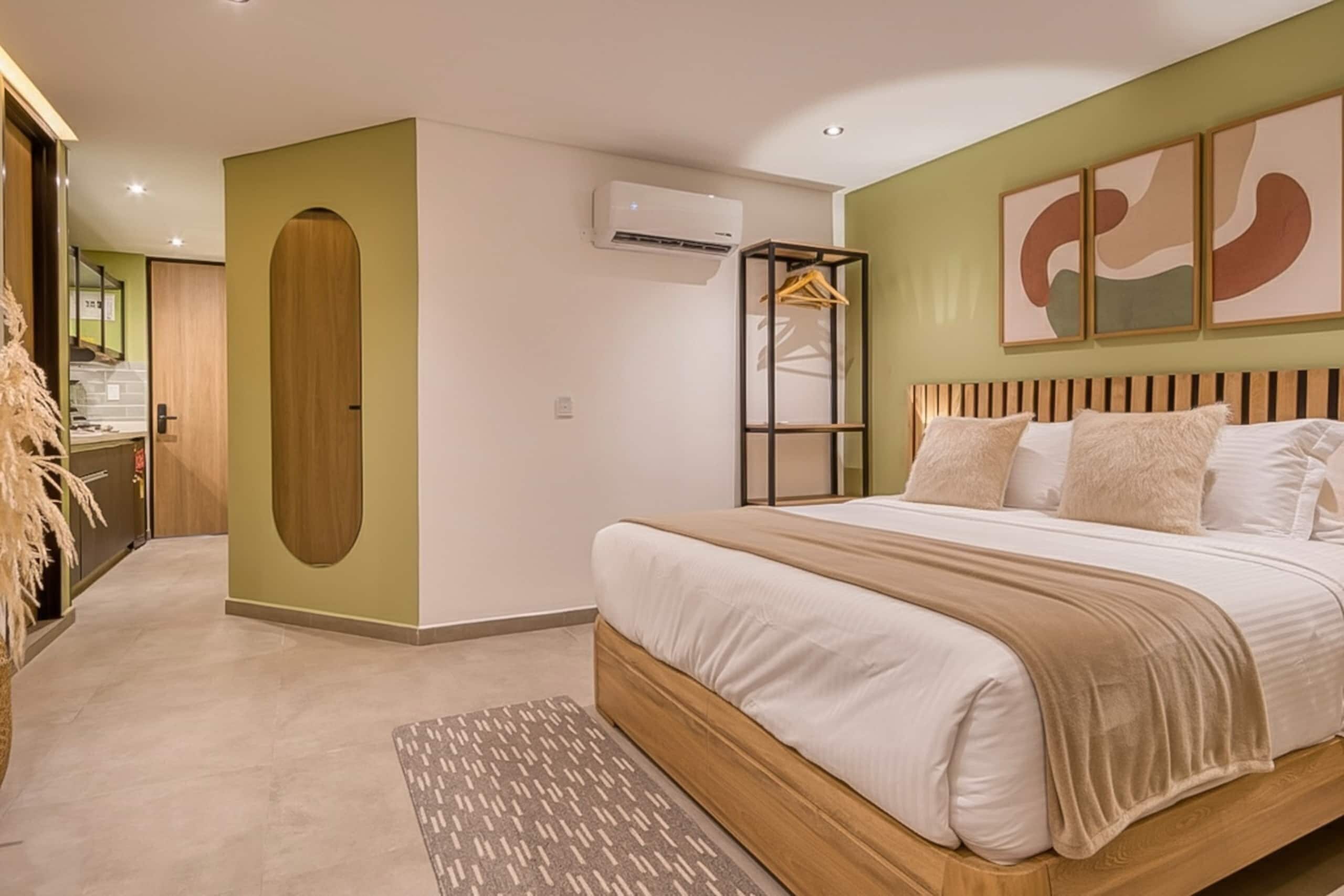 A bedroom with a bed, a wooden headboard, a hanging wardrobe, and a wall-mounted air conditioner.