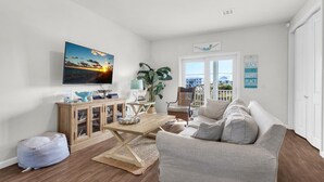 A living room with a sofa, a coffee table, a television, and a view of the outside. - Sea La Vie (Navarre)