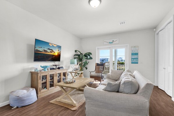 A living room with a sofa, a coffee table, a television, and a view of the outside. - Sea La Vie (Navarre)