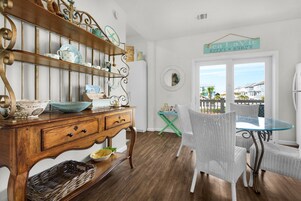 A dining area with a wooden buffet, wicker chairs, and a view of the sea.