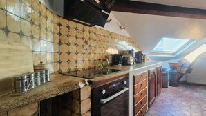 Une cuisine avec un mur recouvert de carreaux, un puits de lumière, une cuisinière et un radiateur.