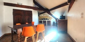 A dining area with a wooden table and orange chairs, a kitchen in the background, and a sloped ceiling with exposed beams. - 2-bedroom apartment in central Cannes with terrace - 800 metres from La Croisette (Cannes)