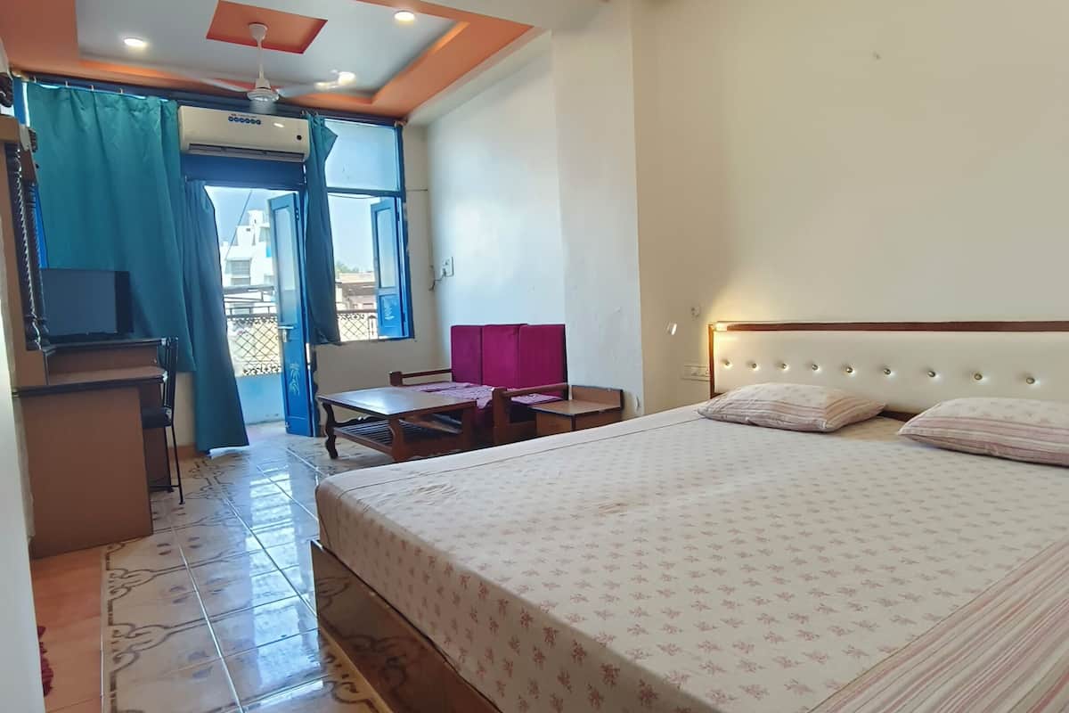 A hotel room with a bed, a desk, a chair, a ceiling fan, and an air conditioning unit.