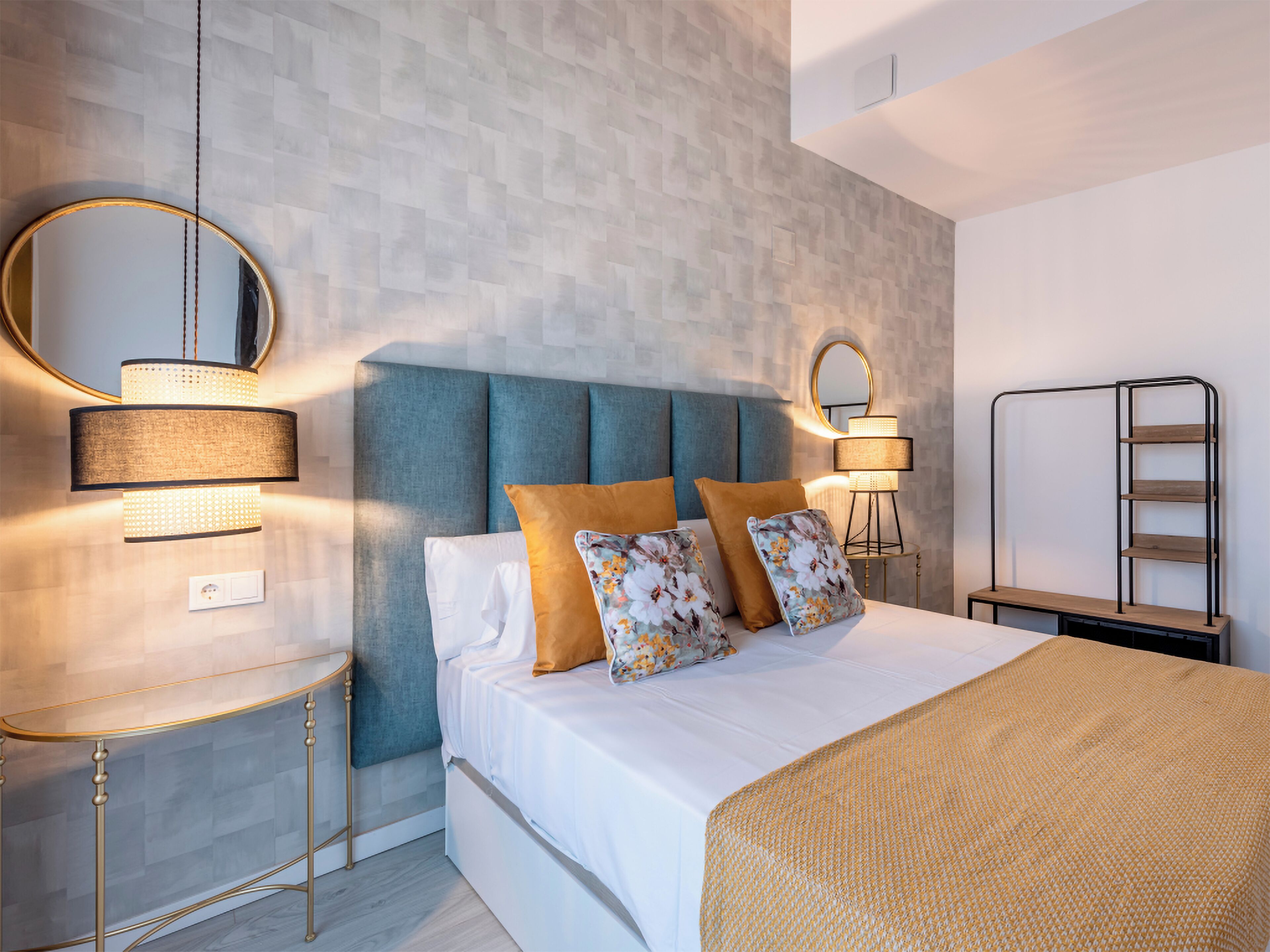A modern bedroom with a bed, bedside tables, a mirror, and a wall-mounted shelf.