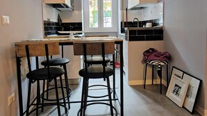 A compact kitchen with a central island, bar stools, and a window with a view of greenery.