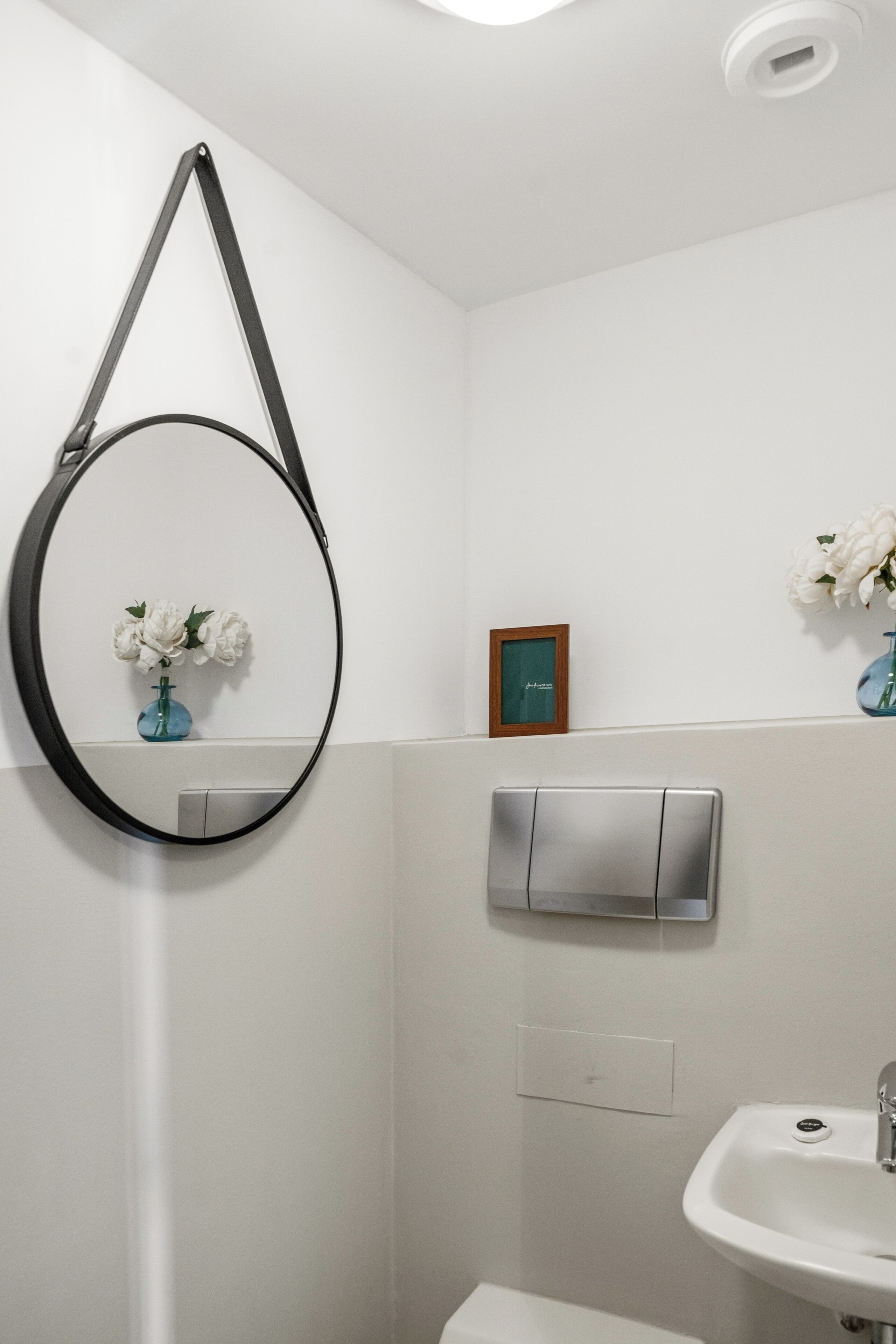 A bathroom with a white sink, a mirror, and a wall-mounted towel dispenser.