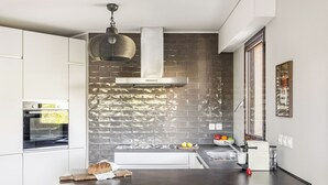 A modern kitchen with a brick backsplash, stainless steel appliances, and a dining area with a table and chairs. - Vivre Cannes (Cannes)