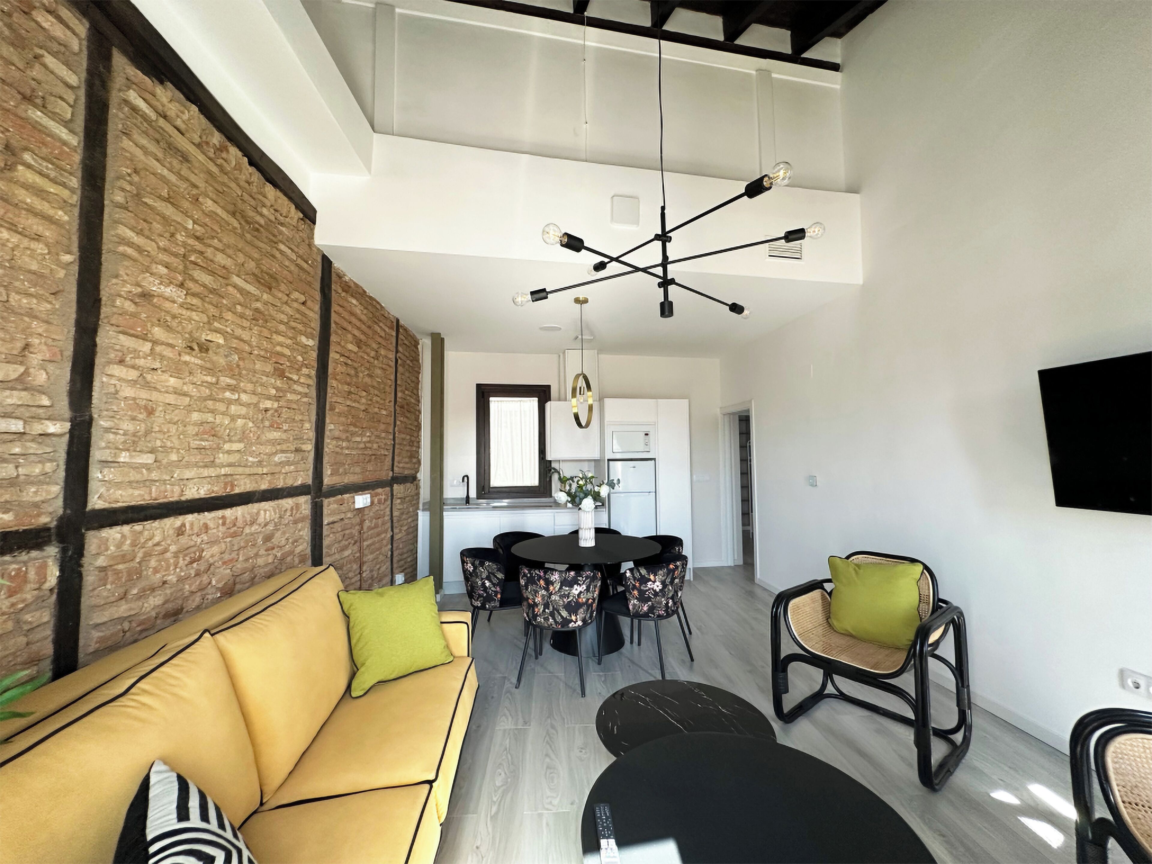 A modern living room with a sofa, chairs, a dining table, and a kitchen in the background.