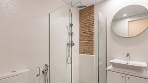 Un bagno moderno con cabina doccia in vetro, lavandino bianco e pavimento a scacchi.