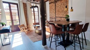 Un'area pranzo moderna con un tavolo e sedie in legno, una pianta in vaso e vista all'esterno attraverso un'ampia finestra.