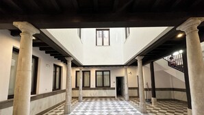 Un ampio atrio con pavimento a scacchi, colonne imponenti e soffitto alto.