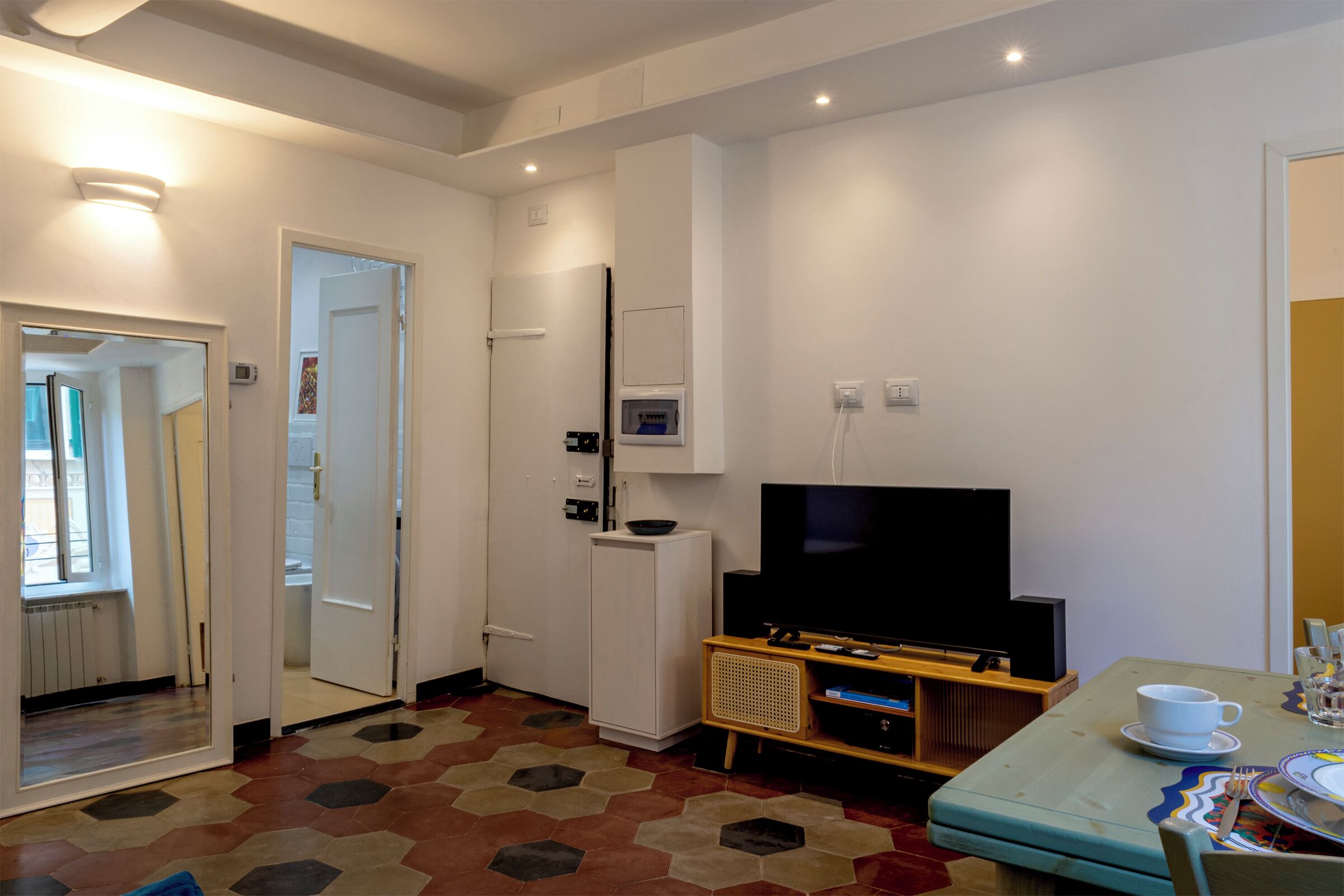 A compact living space with a television, a small refrigerator, a microwave, and a dining area with a table and chairs.