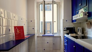 A kitchen with white tiled walls, a window with shutters, a blue countertop, and a coffee machine. - Il Campanile by Wonderful Italy  (Camogli)