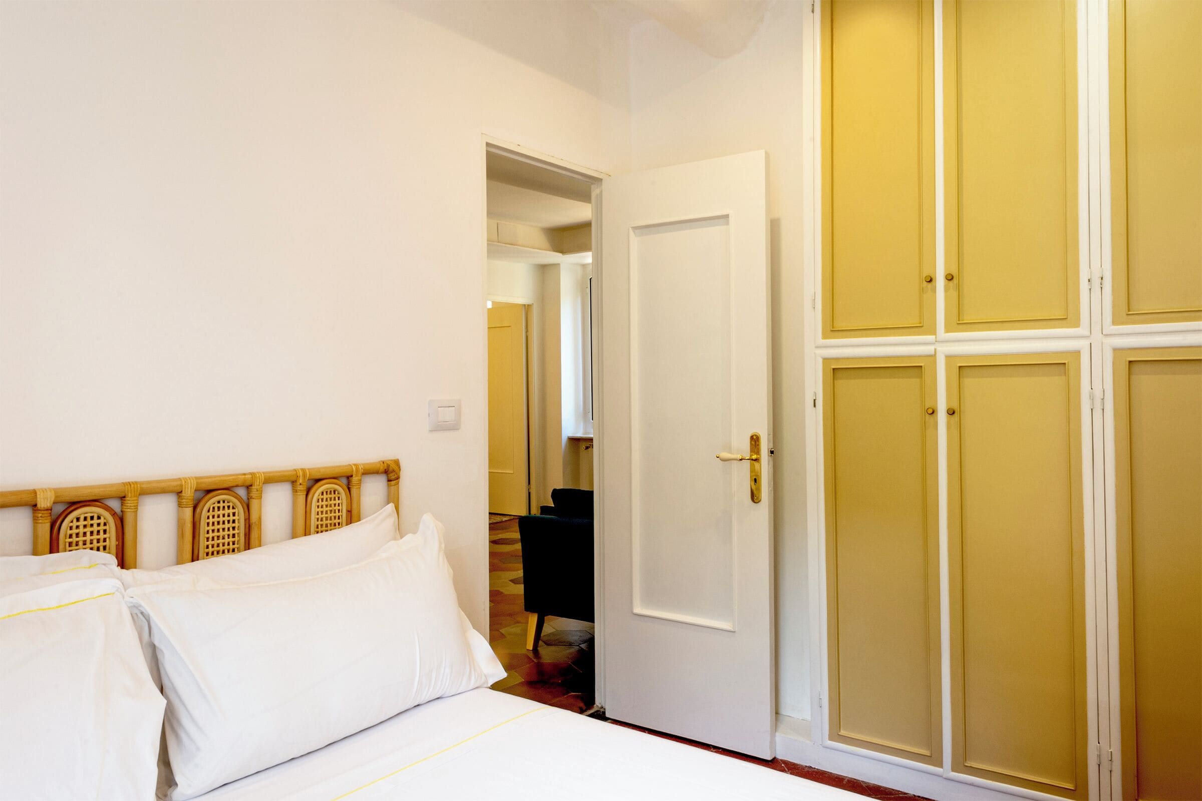 Een hotelkamer met een bed, een kledingkast en een deur die naar een andere kamer leidt.