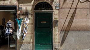 A green door with a brass plate, a mannequin with clothes, and a signboard with numbers. - Il Campanile by Wonderful Italy  (Camogli)
