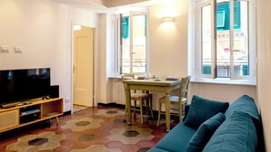 A living room with a television, a dining table with chairs, and a sofa. - Il Campanile by Wonderful Italy  (Camogli)