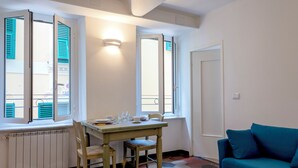 A room with a dining table set for four, two chairs, a blue sofa, and a door. - Il Campanile by Wonderful Italy  (Camogli)