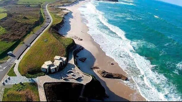 Vista aérea de una zona costera con carretera, playa y edificios.